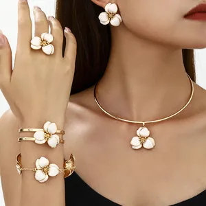 Detail of white enamel flower jewelry set featuring earrings, necklace, ring, and bracelet