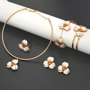 Elegant gold jewelry set with white enamel flowers including necklace and earrings.