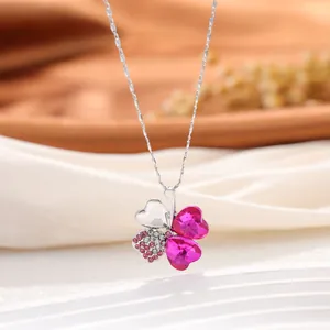 Gros plan d'un pendentif trèfle à quatre feuilles avec cristaux roses en forme de cœur