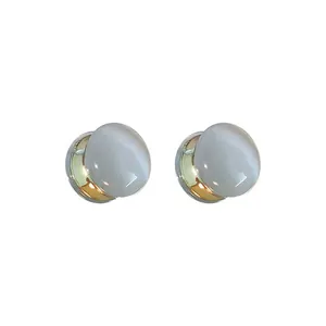 Primer plano de clips de oreja magnéticos con piedra de ojo de gato y base dorada