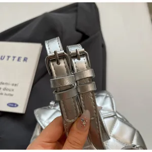 Gros plan du sac à dos argenté matelassé montrant les sangles à boucle réglables