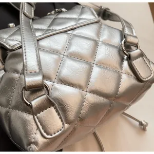 Détail d'un sac seau matelassé argenté montrant la texture et les anneaux métalliques