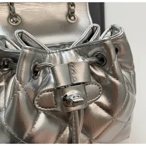 Détail d'un sac seau matelassé argenté avec fermeture à cordon et fermoir tournant