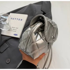 Vue détaillée d'un sac seau matelassé argenté avec finition métallique et chaîne