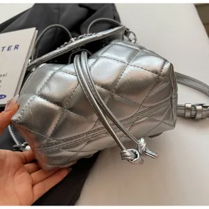 Vue détaillée montrant la texture matelassée argentée d'un sac seau avec cordon de serrage