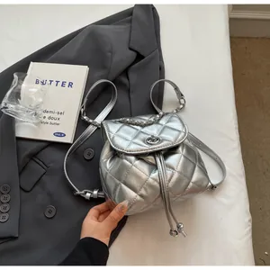 Détail d'un sac à dos seau matelassé argenté avec bandoulière chaîne sur un blazer