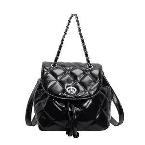 Détail de sac à dos matelassé noir avec fermeture à cordon et poignée en chaîne.