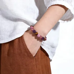Detail view of a colorful natural stone beaded bracelet with tiger eye on a wrist.