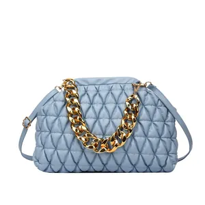 Detailansicht einer hellblauen gesteppten Handtasche mit einer dicken goldenen Kette.