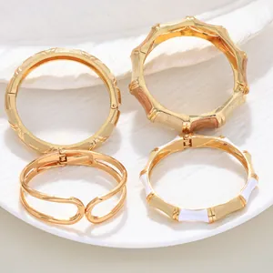 Detailed view of four gold-colored enamel bangles with bamboo and hollow designs