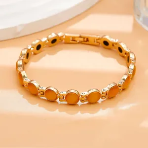 Primo piano di un elegante bracciale dorato con maglie in pietra occhio di gatto arancio