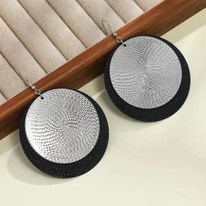 Detalle de los pendientes colgantes redondos de niveles en plata y negro texturizado