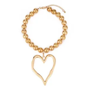 Chunky gold bead necklace with large irregular hollow heart pendant on white background