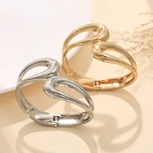 Vista dettagliata di due bracciali aperti in metallo irregolare in oro e argento