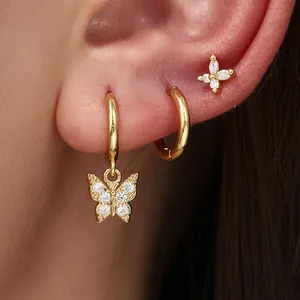 Macro detail of stylish gold butterfly hoop earring set with sparkling CZ stones on ear.