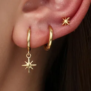 Detailed close-up of stylish gold hoop earrings featuring star charms on a model