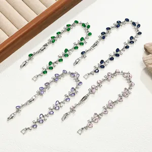 Detailweergave van tak-armbanden met groene, blauwe, paarse en roze sprankelende strassteentjes.