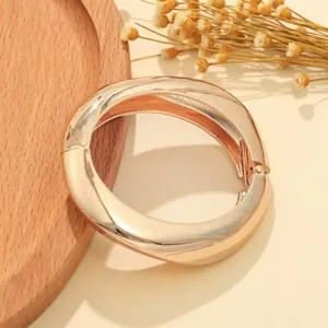 Dettaglio di un bracciale in metallo oro rosa con finitura lucida a specchio