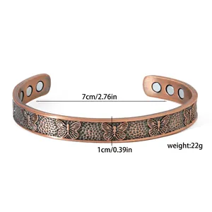 Close-up of antique copper magnet bracelet with butterfly pattern and size markers