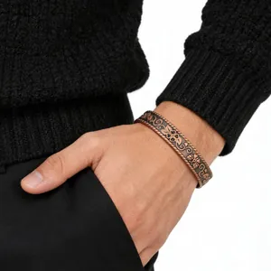 Close-up detail of antique red copper bracelet with intricate floral relief on a wrist