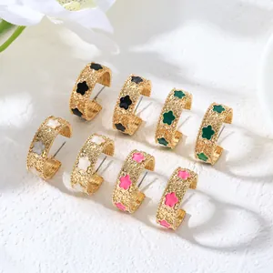 Vue détaillée de boucles d'oreilles créoles dorées avec motifs floraux en quatre couleurs.