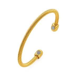 Detailed view of a gold-plated magnetic twisted cable cuff bracelet on white