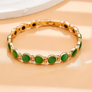 Dettaglio di un bracciale a maglie dorate con pietre occhio di gatto verde lucido.