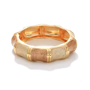 Close-up of the elegant malt yellow marble enamel texture on a gold-toned alloy bangle.