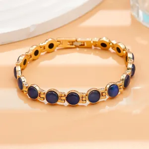 Primo piano di un elegante bracciale in oro con pietre occhio di gatto blu scuro a maglie