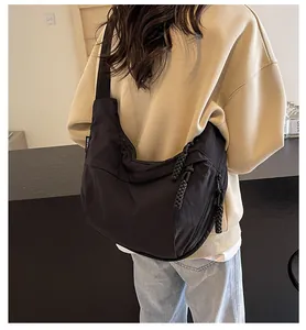 Detailed view of a black canvas dumpling bag worn as a crossbody bag by a model