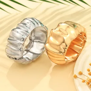 Detailed view of chunky gold and silver irregular pleated bangles with unique texture.