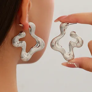 Detail view of large silver fluid wavy earrings with retro striped texture for women