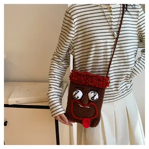 Detailansicht einer originellen braunen Häkelhandytasche mit lustigem Gesicht an Model