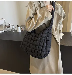 Lifestyle detail of a stylish black quilted bubble tote bag worn by a model in a café.