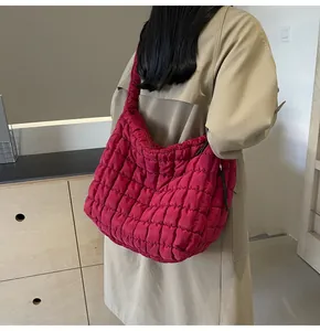 Detailed view of large quilted magenta puffer bag on shoulder with beige trench coat