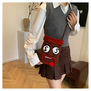 Model trägt eine kreative handgehäkelte Handytasche mit lustigem Cartoon-Gesicht