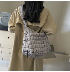 Close-up back view of gray quilted bubble shoulder bag styled with beige trench coat