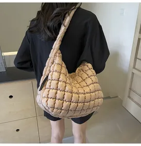 Back view of model carrying a large beige puffy bubble shoulder bag in a home setting