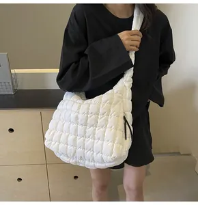 A detailed view of a stylish white quilted bubble shoulder bag worn by a model