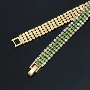 Detail view of luxury gold-tone bracelet featuring four rows of green and clear crystals