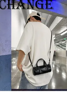 Close-up detail view of a black mini cylindrical crossbody bag worn by a male model