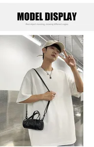 Detailed view of the mini black barrel bag worn by a model for size perspective