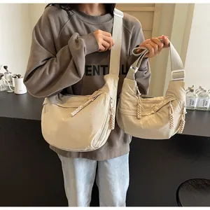 Comparison of large and small beige canvas dumpling crossbody bags shown on a model
