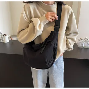 Detailed view of a casual black nylon crescent crossbody bag being worn by a model.