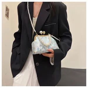 Dettaglio della borsa ricamata in stile cinese con elegante manico di perle.
