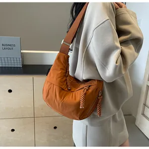 Model wearing a casual orange-brown dumpling shoulder bag in a modern setting