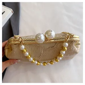 Detail of champagne gold evening bag with large pearl clasp and beaded handle strap
