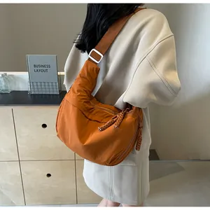 Lifestyle view of a large orange canvas crossbody dumpling bag worn by a female model