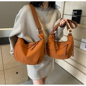Close-up of casual orange dumpling shoulder bags in two sizes worn by a model