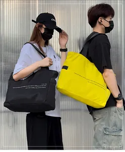Bolsos tote grandes de nailon en negro y amarillo usados por modelos con estilo